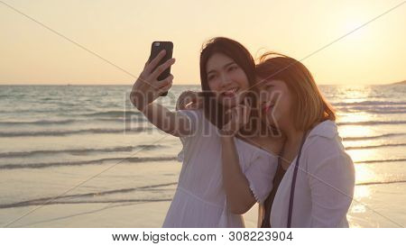 Young Asian Lesbian Couple Using Smartphone Taking Selfie Near Beach. Beautiful Women Lgbt Couple Ha