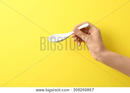 Woman Holding Empty Miso Soup Spoon On Color Background, Closeup. Space For Text