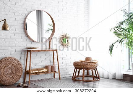 Hallway Interior With Big Round Mirror, Table And Decor Near Brick Wall