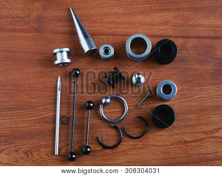 Jewelry Piercing Set. Piercing Accessories On Wooden Background. Stretching For Ear Tunnels , A Cath