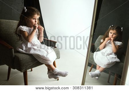 Interaction Of Children With Adult World. Cute Girl Trying To Do Bright Make Up For Being Older. Lit