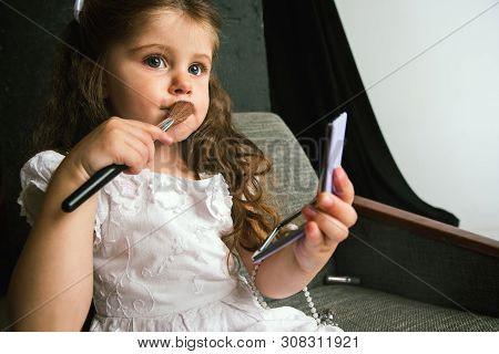 Interaction Of Children With Adult World. Cute Girl Trying To Do Bright Make Up For Being Older. Lit