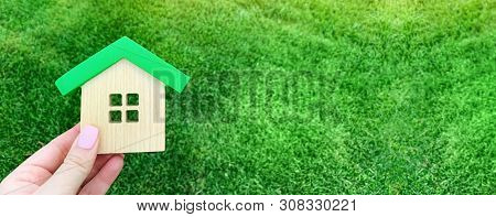 Miniature Wooden House On Green Grass. Real Estate Concept. Eco-friendly And Energy Efficient House.