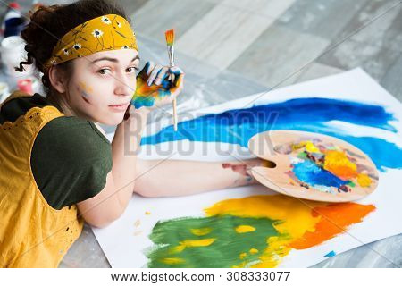 Fine Art Hobby. Top View Of Talented Female Painter, Lying Down On Floor, Creating Abstract Artwork.