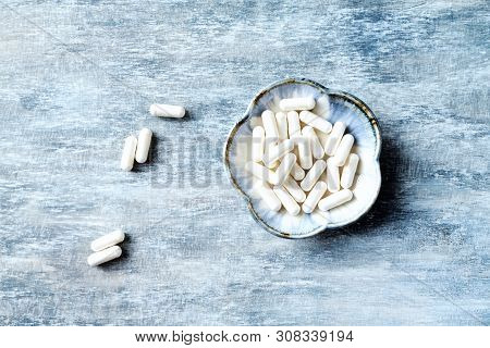 Theanine Capsules. Dietary Supplement.  Rustic Wooden Background. Top View. Copy Space.