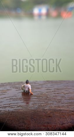 Mini Figure Toy Old Man Sit At Scratch Wooden Balcony At River Side With Copy Or Negative Space For 