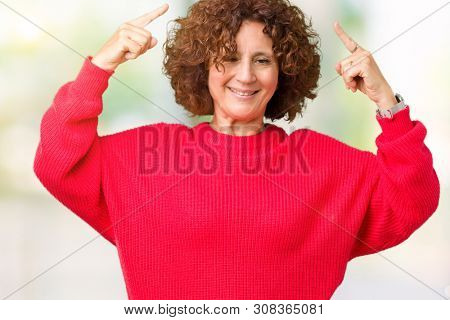 Beautiful middle ager senior woman red winter sweater over isolated background Smiling pointing to head with both hands finger, great idea or thought, good memory