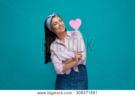 Trendy Happy Woman In White Shirt And Jeans Keping Pink Paper Heart And Posing On Blue Isolated Back