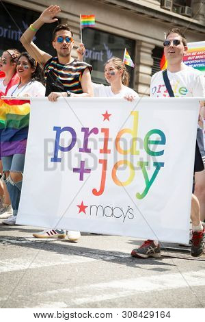 2018 JUNE 24 NEW YORK: NYC Pride March participants walk behind the Macys Pride and Joy banner on the 5th Ave parade route.