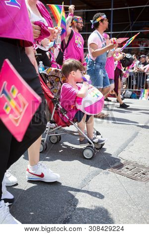 2018 JUNE 24 NEW YORK: NYC Pride March participants wearing pink and rainbow colored T-Mobile shirts walk along the 5th Ave parade route.