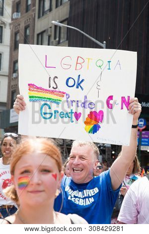 2018 JUNE 24 NEW YORK: NYC Pride March participant holds a sign that says LGBTQIA Is OK on the 5th Ave parade route.