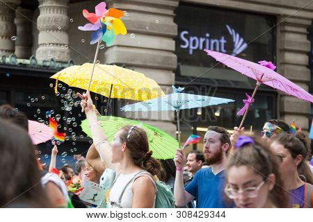 2018 JUNE 24 NEW YORK: NYC Pride March participants walk with colorful rainbow umbrellas at 23rd St and 5th Ave.