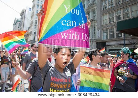 2018 JUNE 24 NEW YORK: NYC Pride March participant holds a sign that says You Can Sit With Us on the 5th Ave parade route.