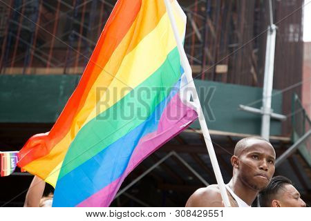 2018 JUNE 24 NEW YORK: NYC Pride March participants wave rainbow flags as they walk along the parade route on 5th Ave.