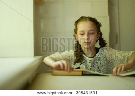 Pupil In School Uniform With Braids. Girl Schoolgirl At School With Book In School Uniform. Training