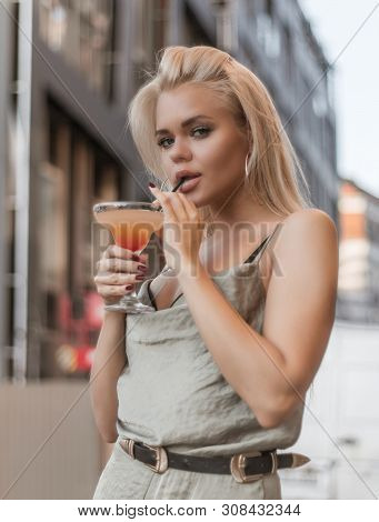 Young Beautiful Woman Is Enjoying Her Drink While Posing For Photographer.
