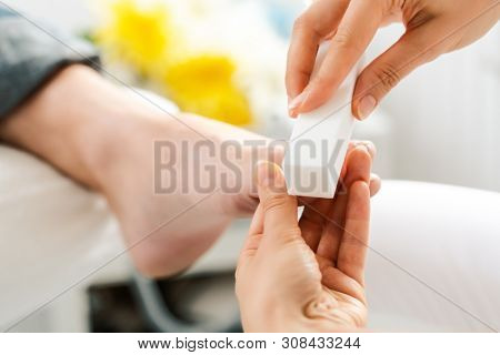 Woman podiatrist polishing feed of men during pedicure with file