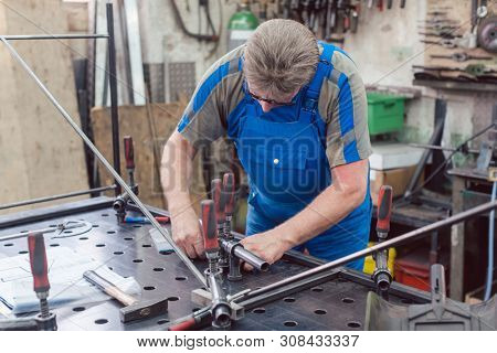 Worker in Metal workshop with tools and workpiece concentrating on his job