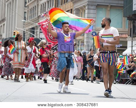 2018 JUNE 24 NEW YORK: NYC Pride March participants wave rainbow flags as they walk along the parade route on 5th Ave.
