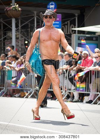 2018 JUNE 24 NEW YORK: NYC Pride March participant wearing only black low-cut short-shorts and high heel outfit walks along the 5th Ave parade route.