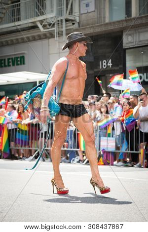 2018 JUNE 24 NEW YORK: NYC Pride March participant wearing only black low-cut short-shorts and high heel outfit walks along the 5th Ave parade route.