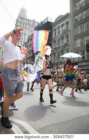 2018 JUNE 24 NEW YORK: NYC Pride March participants walk with colorful rainbow umbrellas at 23rd St and 5th Ave.