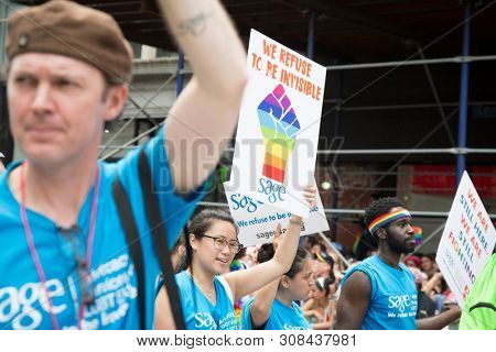 2018 JUNE 24 NEW YORK: NYC Pride March Sage participant holds a sign that says We Refuse To Be Invisible on the 5th Ave parade route.
