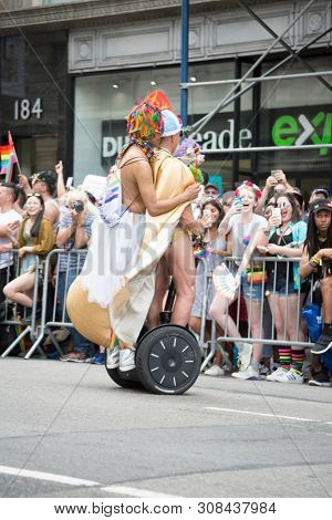 2018 JUNE 24 NEW YORK: Two NYC Pride March participants dressed in Roman gladiator outfits ride on a segway along the 5th Ave parade route.
