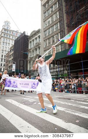 2018 JUNE 24 NEW YORK: NYC Pride March participants wave rainbow flags as they walk along the parade route on 5th Ave.