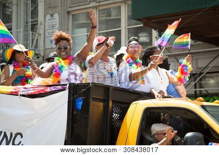 2018 JUNE 24 NEW YORK: NYC Pride March participants wave rainbow flags while riding on a parade float along the 5th Ave route.
