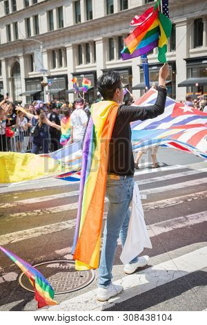 2018 JUNE 24 NEW YORK: NYC Pride March participants wave rainbow flags as they walk along the parade route on 5th Ave.
