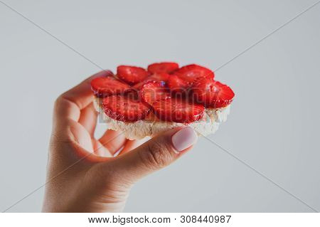 Crispbread With Strawberries In Hand On A Gray Background
