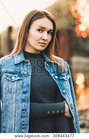 Portrait Of The Attractive, Slender, Beautiful Young Caucasian Blonde Girl In A Jeans Jacket. Smilin