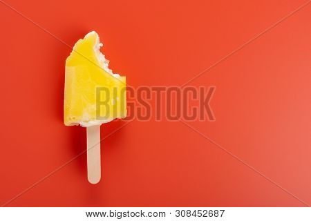 Yellow Popsicle With A Couple Of Bites On An Orange Background