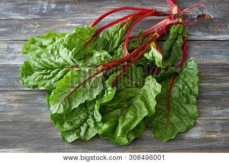 Fresh Raw Leaves Of Chard, Leaf Beets, Mangold, Swiss Chard On A Wooden Table, Close Up