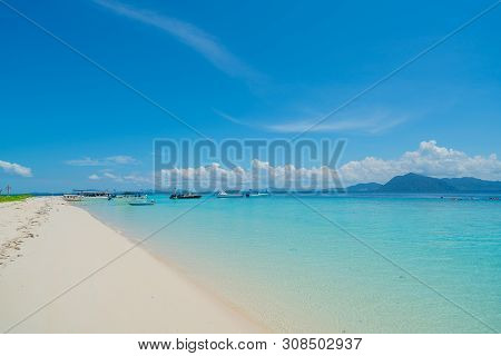 White Coral Sand Beach  With Moored Line-up Of Boats Used To Bring Tourists To Island Surrounded By 