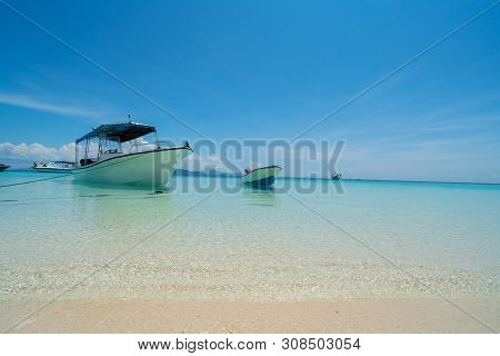 White Coral Sand Beach  With Moored Line-up Of Boats Used To Bring Tourists To Island Surrounded By 