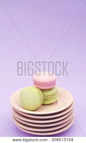 Three Macaroons On A Stack Of Beige Saucers On A Purple Background.