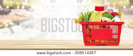 Food And Groceries In Shopping Basket On Wood Table With Blurred Suppermarket In Background, Panoram