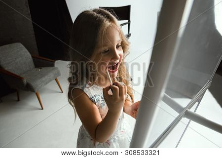 Interaction Of Children With Adult World. Cute Girl Trying To Do Bright Make Up For Being Older. Lit