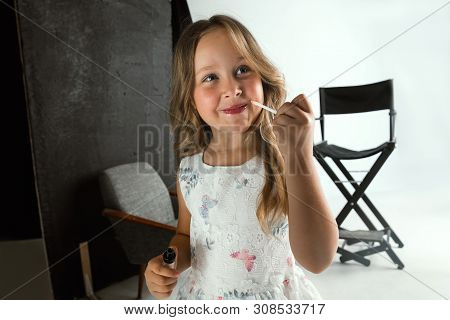 Interaction Of Children With Adult World. Cute Girl Trying To Do Bright Make Up For Being Older. Lit