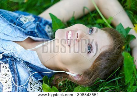 Woman Listening To Music With Headphones At The Park