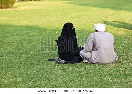 Donna islamica In Burka seduto sul verde con suo marito