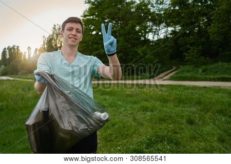 Blogging Concept. A Man Collects Trash From The Forest In The Trash Bag