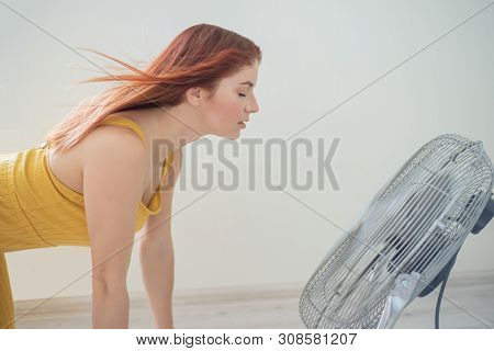 Portrait Of A Beautiful Red-haired Woman In Mustard Overalls Enjoying The Cooling Breeze From A Larg