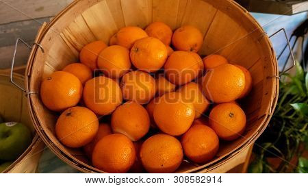 Rattan Basket Filled With Fresh Citrus Fruit On A Buffet Or Market Table Alongside Green Apples In A