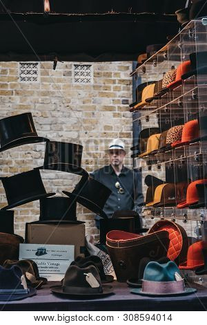 London, Uk - June 22, 2019: Man Behind Hats On Sale At A Stall Inside Spitalfields Market, One Of Th