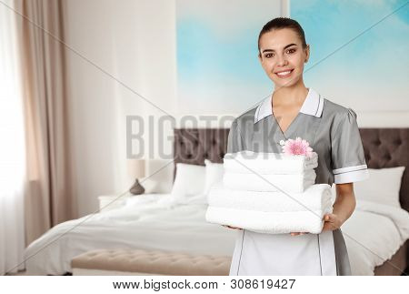 Chambermaid With Stack Of Fresh Towels In Hotel Room. Space For Text