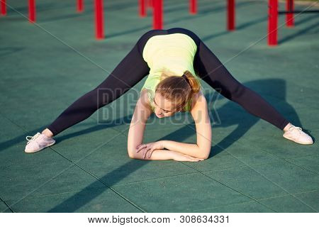 Portrait Of Fit And Sporty Young Woman Doing Stretching In Workout Sports Ground
