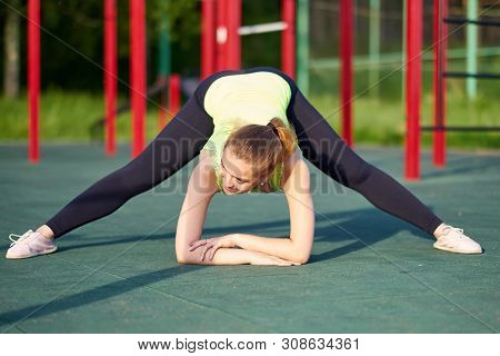 Portrait Of Fit And Sporty Young Woman Doing Stretching In Workout Sports Ground